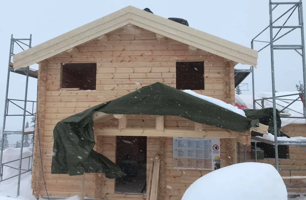Før: inngangen på laftehuset under presenning, med stillas