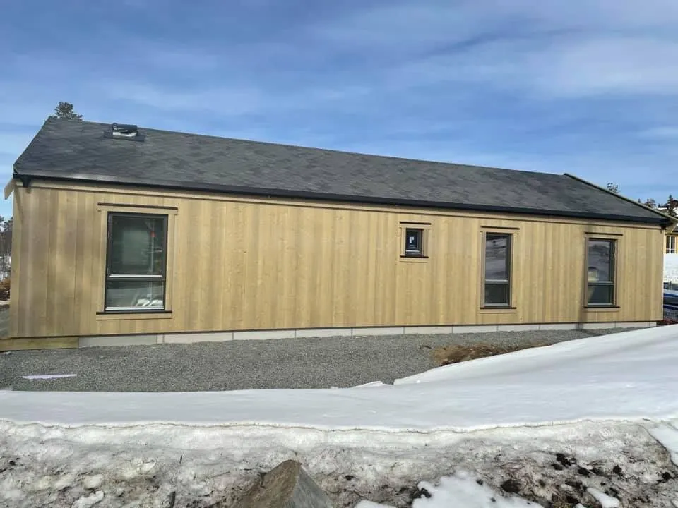 Ferdig lang hytte i stående kledning, med snø rundt
