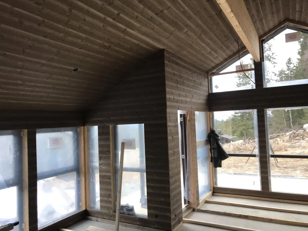Mørkt beiset panel på vegger og i tak, med store vinduer