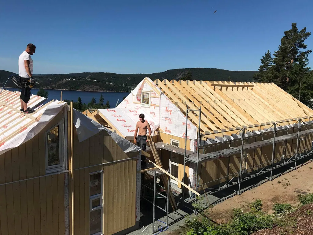 Takarbeid på en hytte, med fjorden i bakgrunnen